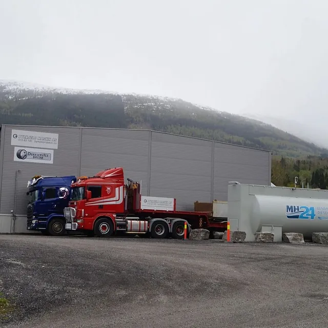 Rød og blå lastebil foran industribygg